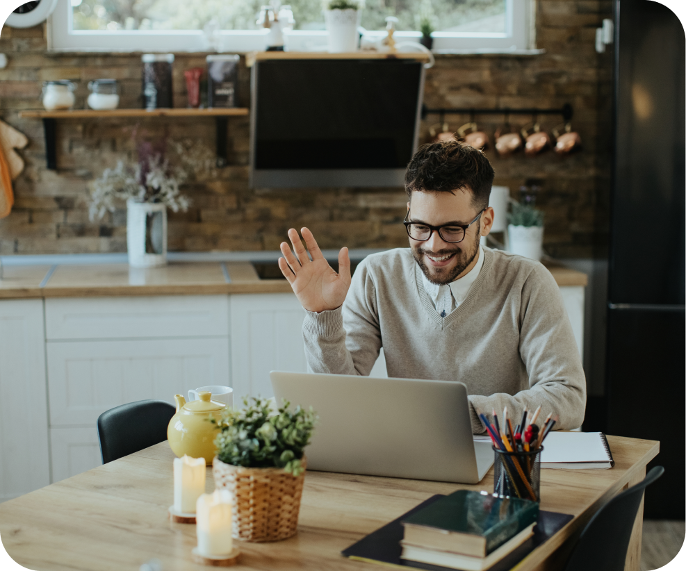 Person waving during video call on laptop at home kitchen workspace with modern internet connectivity
